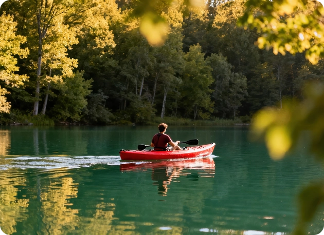Een man in een rode kajak vaart over de rivier met uitzicht op een dichtbegroeid bos
