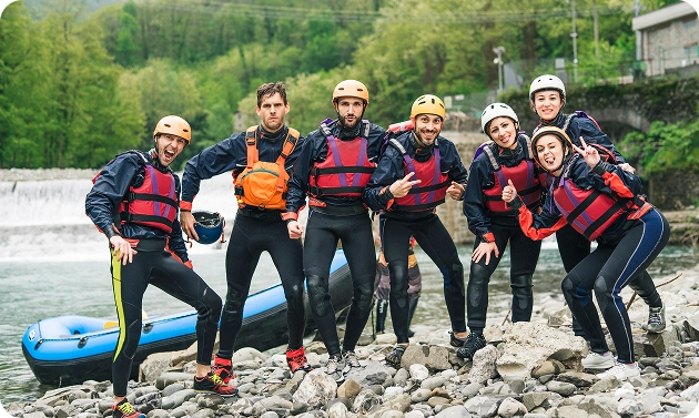 Een groep mensen in sportkleding poseert bij een boot aan de oever van de rivier