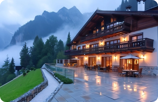Een gezellig chalet met een verlicht terras tegen de achtergrond van mistige bergen