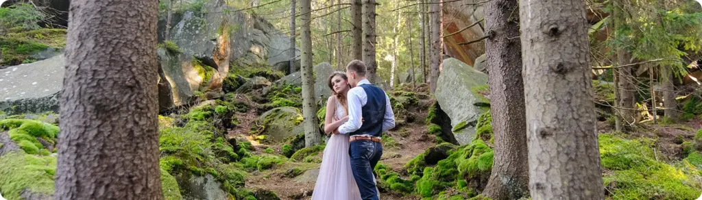 Een verliefd stel knuffelt tussen de bomen en het mos in het bos